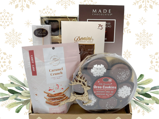 Assorted food items including cookies, candy, and chocolate in a decorative box with a festive background.