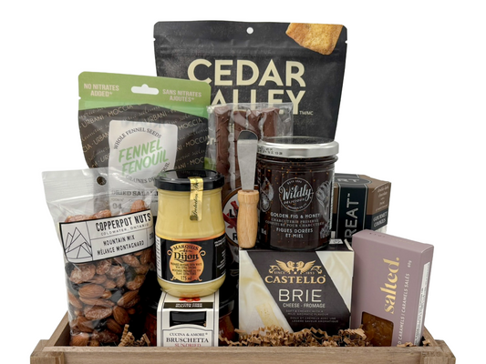 Assorted food items including cheese, nuts, and spreads in a wooden box on a white background. Gift basket idea in Calgary.