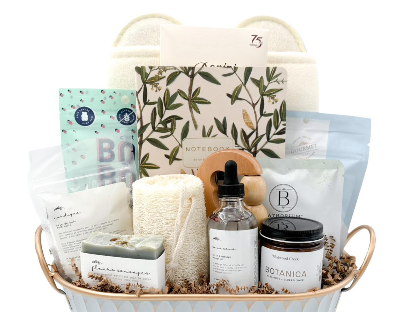 Gift basket with various items including a candle, soap, and a notebook on a white background