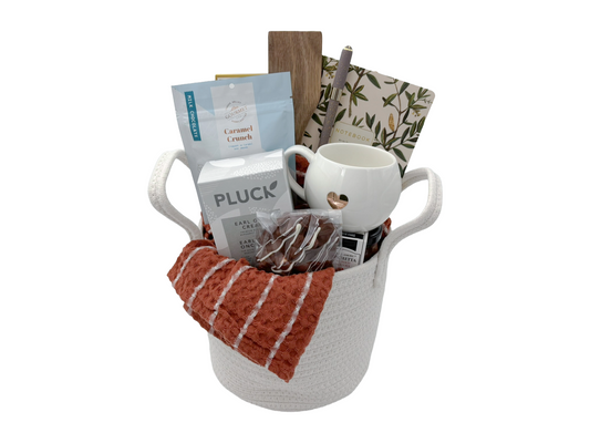 Gift basket with coffee mug, snacks, and tea bags on a white background