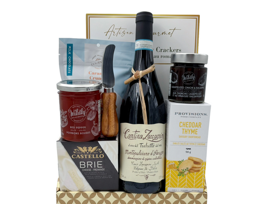 Gourmet gift basket with wine, cheese, and other snacks on a white background