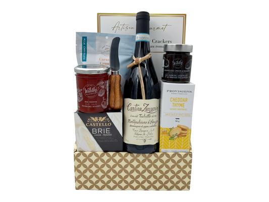 Gourmet gift basket with wine, cheese, and other snacks on a white background