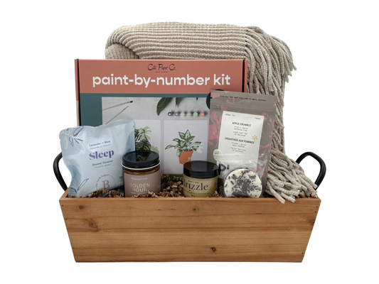 Gift basket with paint-by-number kit, candles, and other items on a white background
